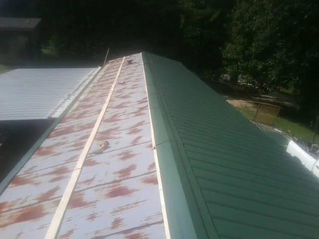 Old rusted panels beside newly installed green metal roofing — Wind Damage Roof Repair by Roofing Brothers in Portola Valley