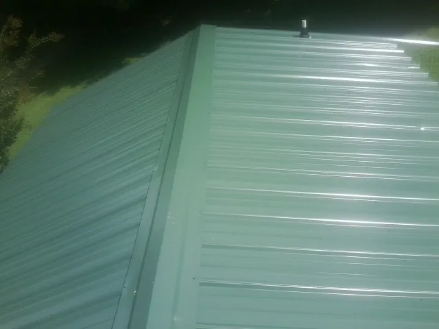 New green metal panels meeting at the ridge of a roof — Flat Roof Repair work by our crew in Portola Valley