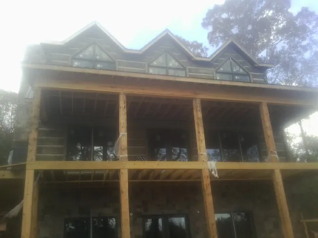 Dormers and porch framing on a large log home under construction — Roof Coating work by our crew in Portola Valley