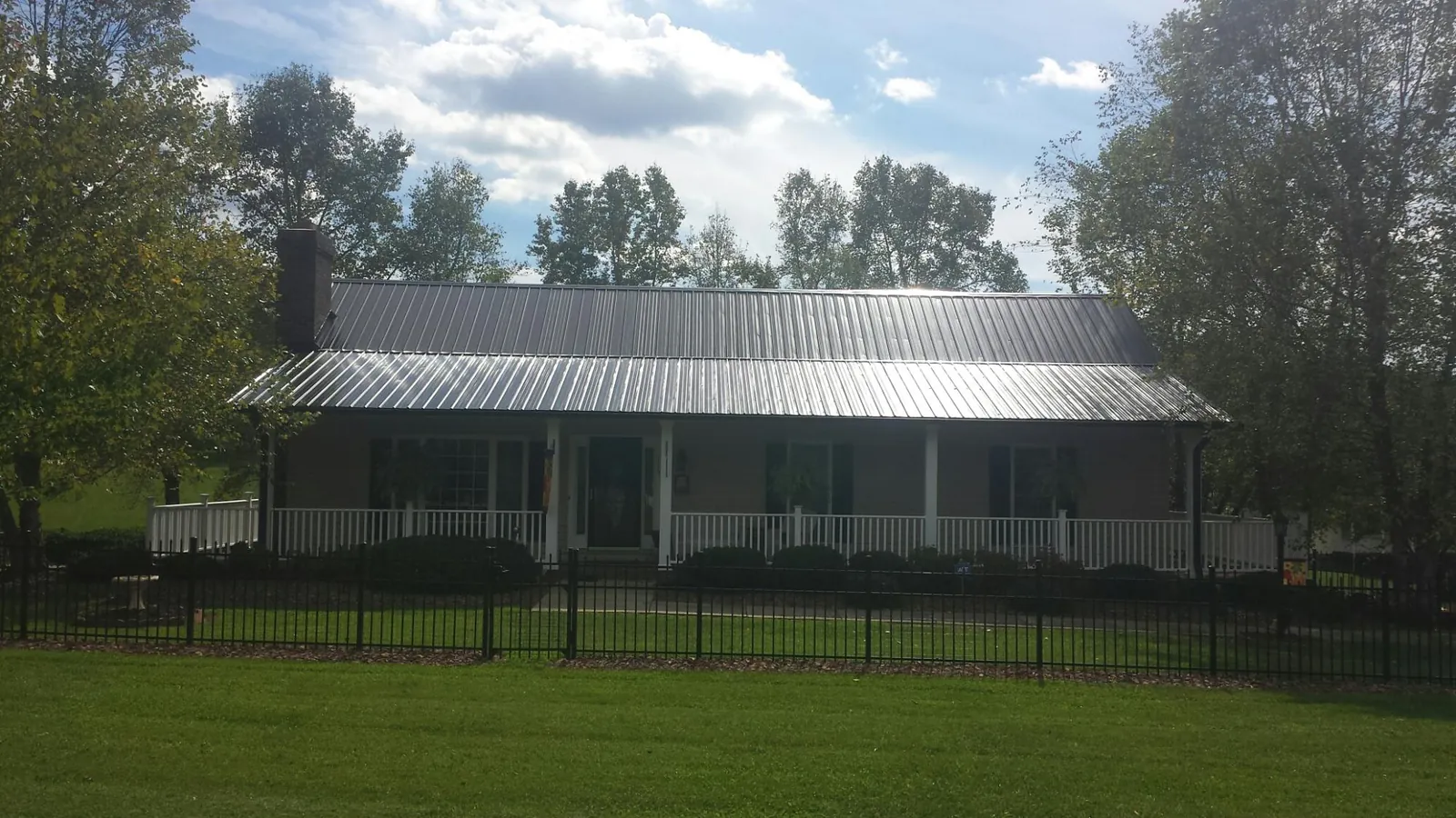 Gray metal roof on a brick ranch with a full width front porch — Gutter Guard Installation work by our crew in Portola Valley