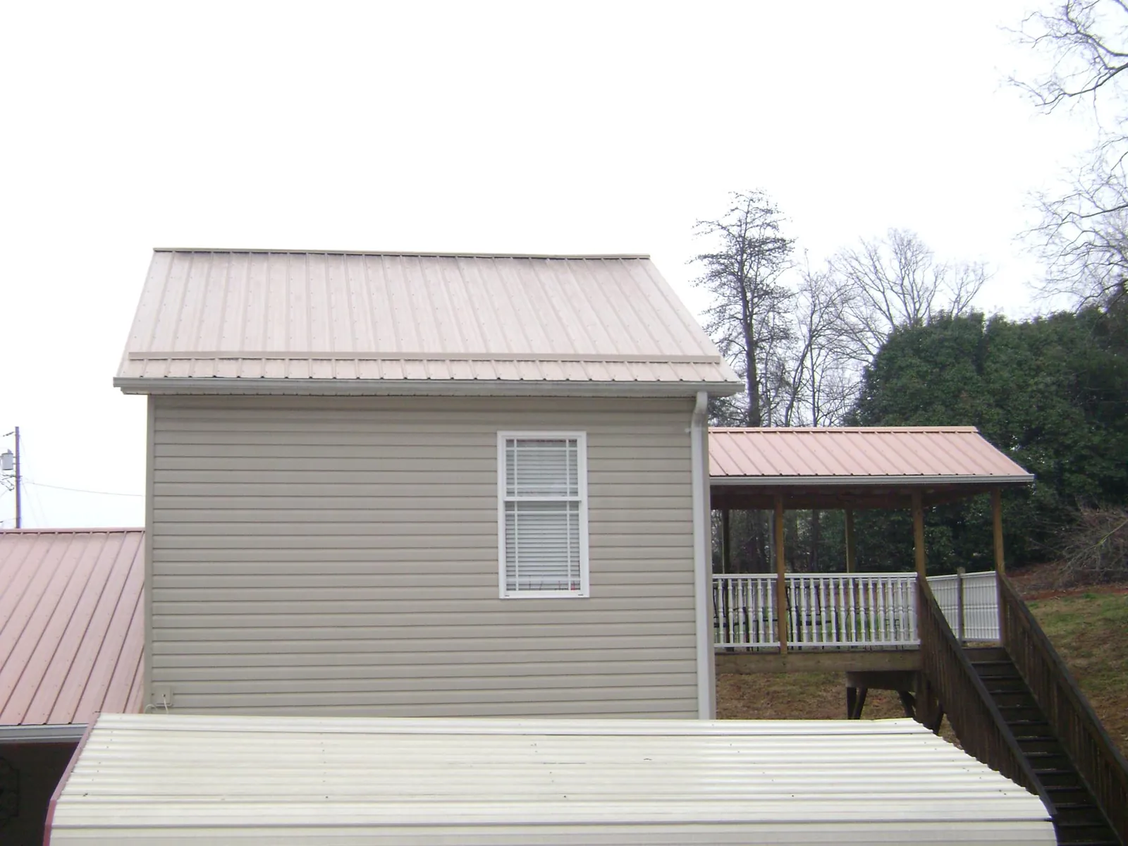 Tan metal roofs on a two story addition and attached porch, from a Roof Replacement job in Portola Valley