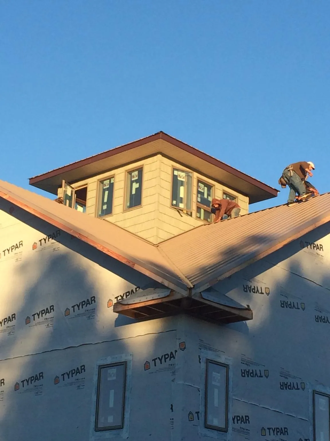 Roofers working around a rooftop cupola on a new metal roof at sunset — Roof Waterproofing in Portola Valley by Roofing Brothers